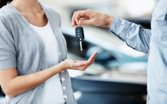 Cropped view of a woman receiving a key to her new vehicle